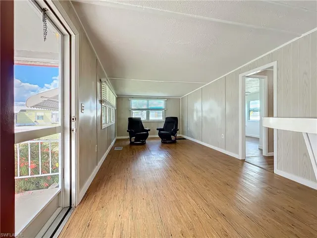 Unfurnished room featuring wood finished floors, baseboards, visible vents, ornamental molding, and a textured ceiling