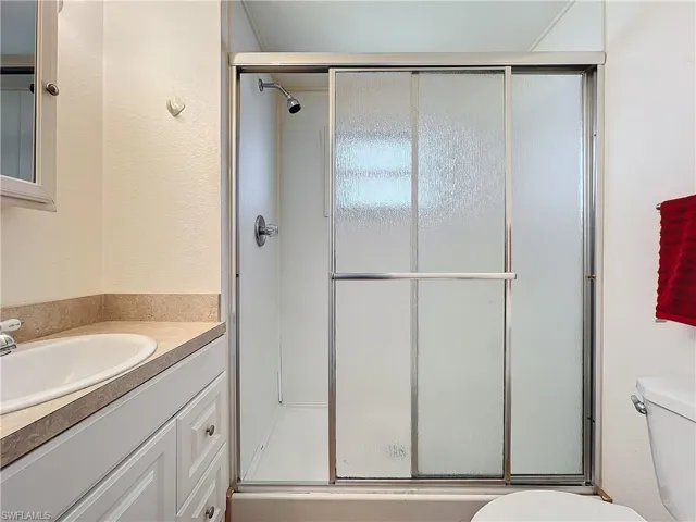 Full bath featuring vanity, a shower stall, and toilet