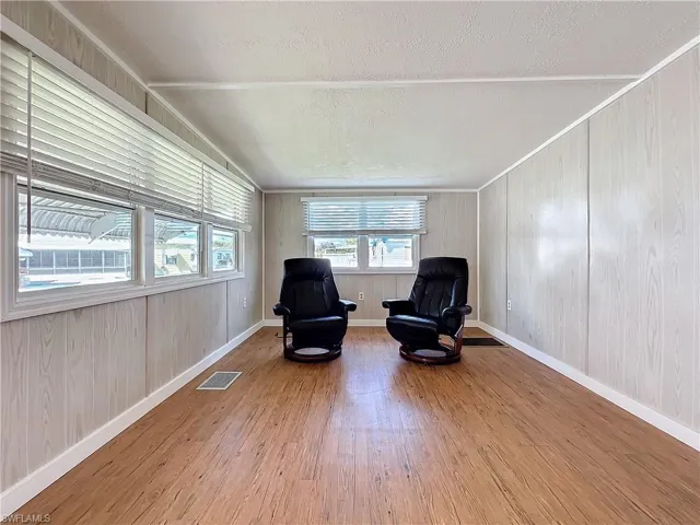 Sitting room with lofted ceiling, wood finished floors, visible vents, and baseboards