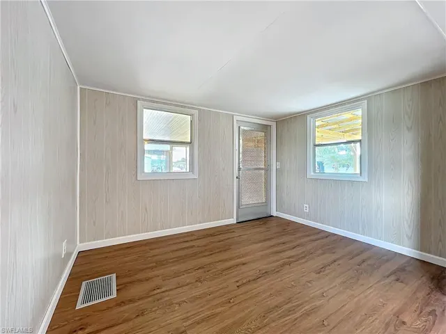 Unfurnished room featuring wood finished floors, visible vents, and baseboards