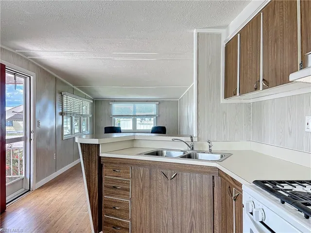 Kitchen with light countertops, light wood-style flooring, a peninsula, a textured ceiling, and a sink