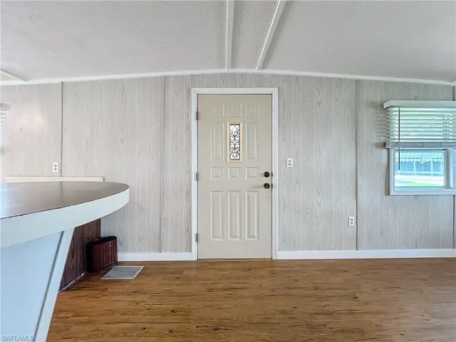 Foyer entrance featuring beam ceiling, wood finished floors, and baseboards
