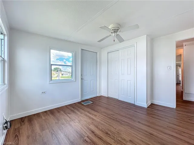 Unfurnished bedroom with a ceiling fan, visible vents, baseboards, dark wood-type flooring, and a closet