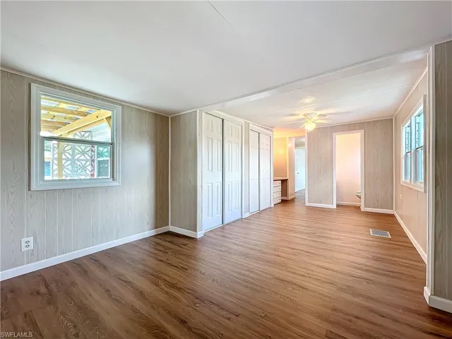 Unfurnished room featuring a wealth of natural light, visible vents, baseboards, and wood finished floors