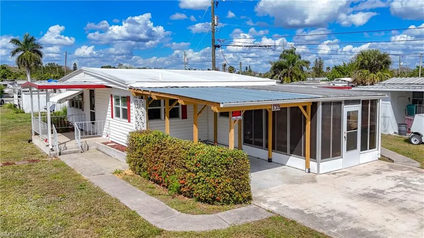 Back of property with a lawn, a sunroom, and metal roof