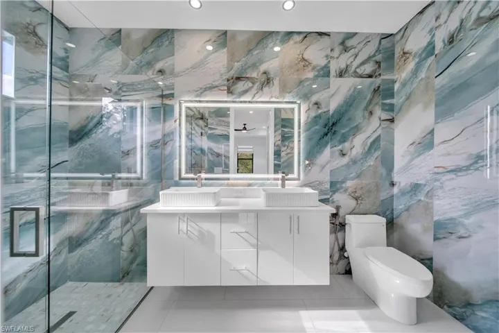 Full luxury bath featuring tile walls, double vanity, a marble finish shower, and tile patterned floors