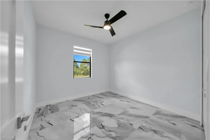 Bedroom 1, with a ceiling fan and light marble finish flooring