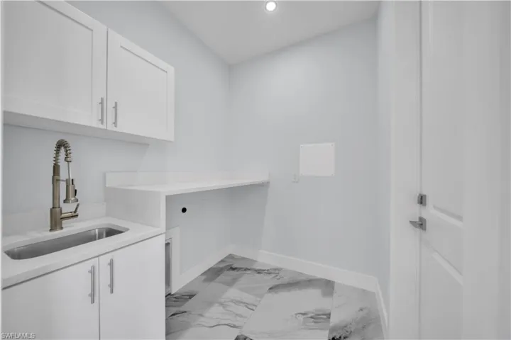 Laundry area with light marble finish flooring, recessed lighting, hookup for an electric dryer, and cabinet space