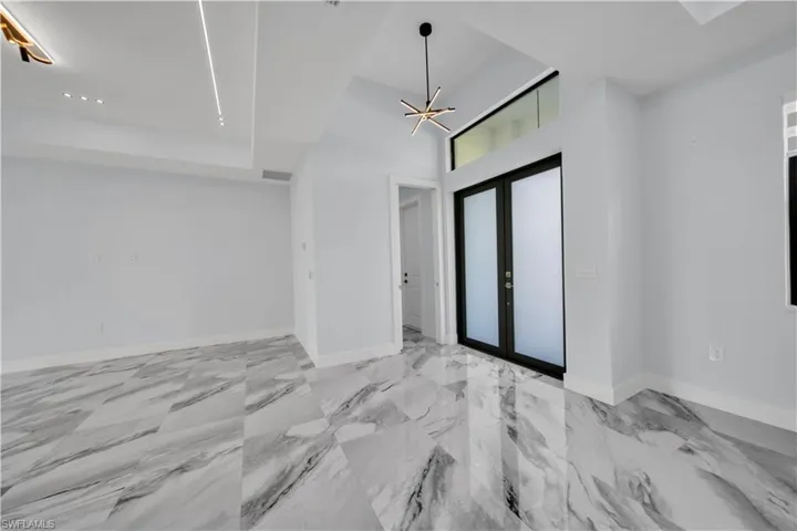 Entrance with french doors, light marble finish floors, and a high ceiling