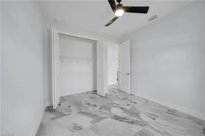 Bedroom with ceiling fan, a closet, and marble finish flooring