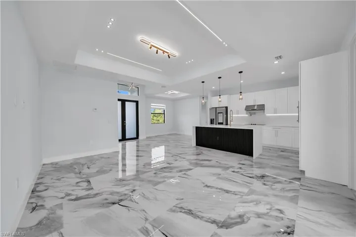 Living room featuring a raised ceiling, a ceiling fan, and french doors
