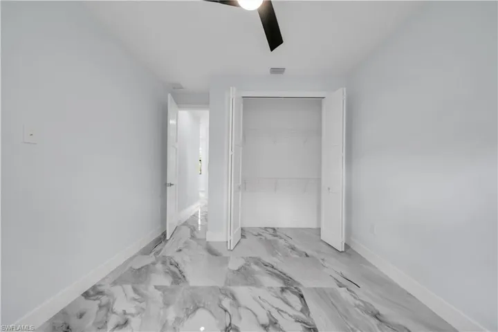 Bedroom 2,  closet, ceiling fan, and light marble finish floors