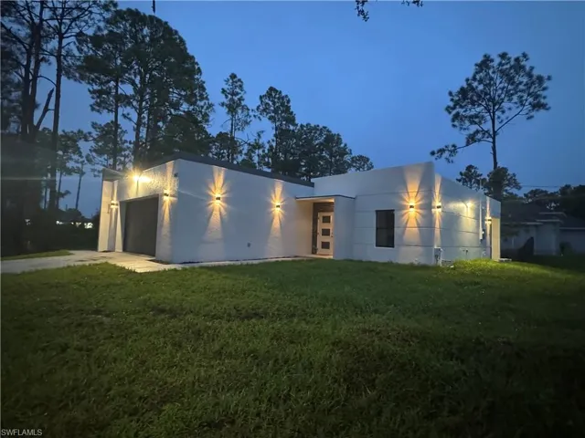 Contemporary home with a garage, a front yard, stucco siding, and driveway