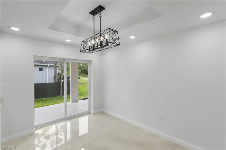 Unfurnished dining area with a tray ceiling, a chandelier, and recessed lighting