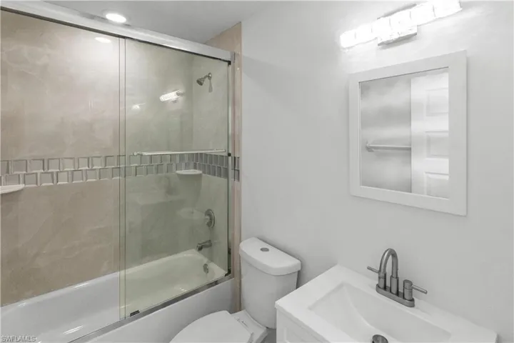 Full bathroom with enclosed tub / shower combo and vanity
