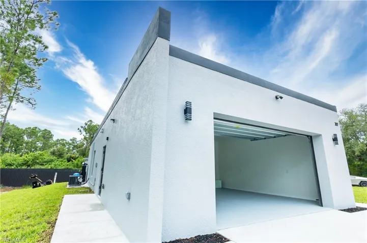 View of property exterior featuring stucco siding, a lawn, and driveway