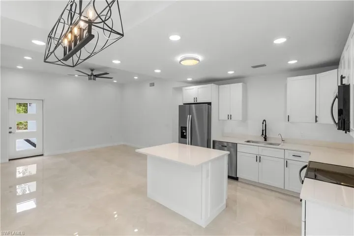 Kitchen with white cabinetry, a kitchen island, hanging light fixtures, appliances with stainless steel finishes, and recessed lighting