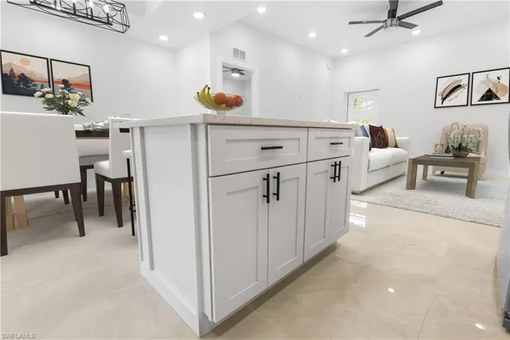 Kitchen with a center island, open floor plan, recessed lighting, a ceiling fan, and light stone counters