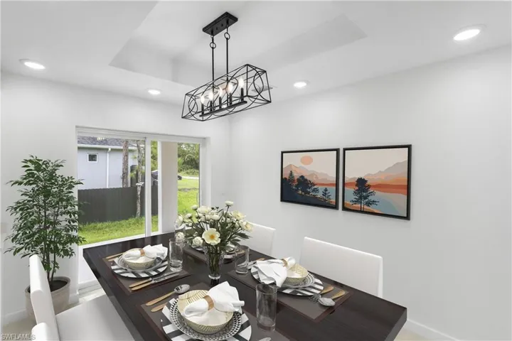 Dining space featuring a tray ceiling, a chandelier, and recessed lighting