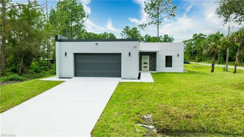 Modern home featuring stucco siding, concrete driveway, a garage, and a front yard