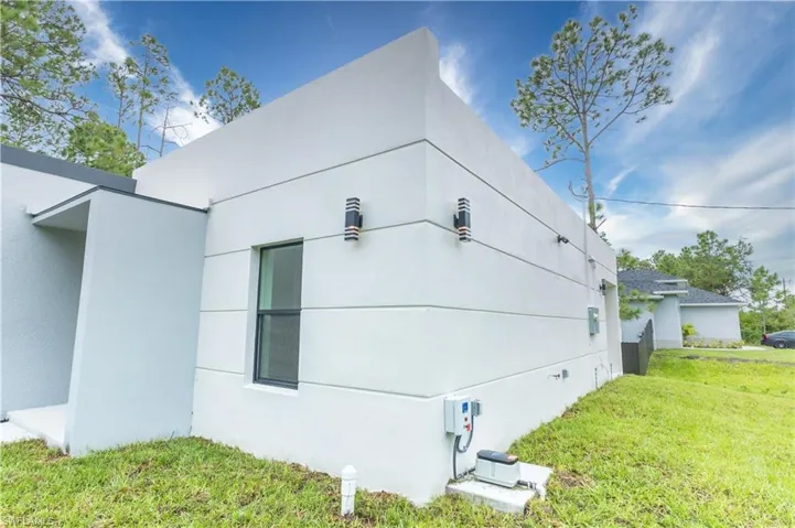 View of side of property featuring a lawn and stucco siding