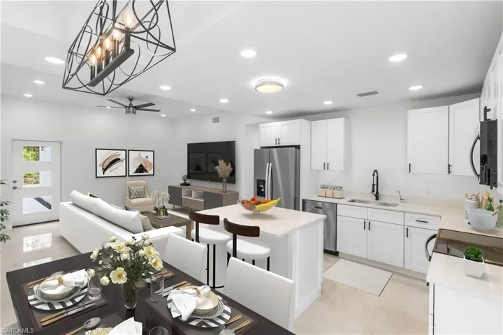 Kitchen featuring white cabinetry, open floor plan, stainless steel appliances, decorative light fixtures, and recessed lighting