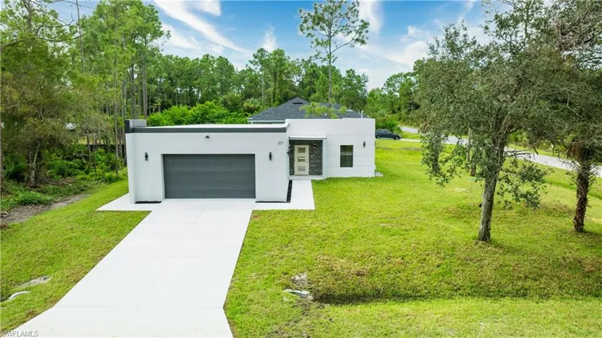 Contemporary house with stucco siding, concrete driveway, a front lawn, and a garage
