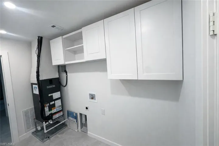 Laundry room with heating unit, washer hookup, hookup for an electric dryer, and cabinet space