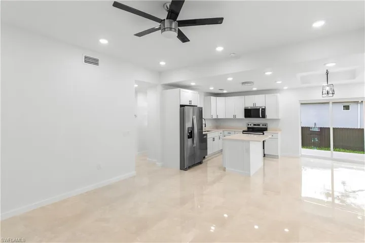 Kitchen featuring light countertops, a center island, white cabinetry, appliances with stainless steel finishes, and decorative light fixtures