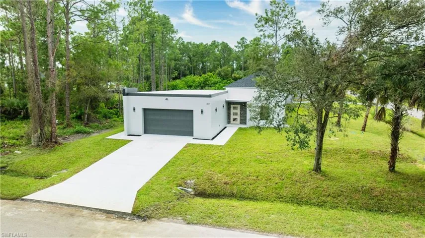 Contemporary home featuring stucco siding, concrete driveway, a garage, and a front yard