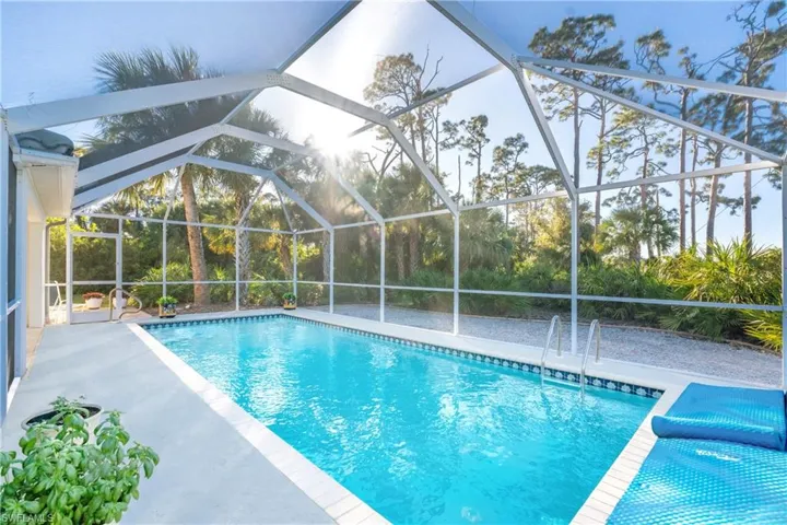 View of swimming pool with glass enclosure and a patio area