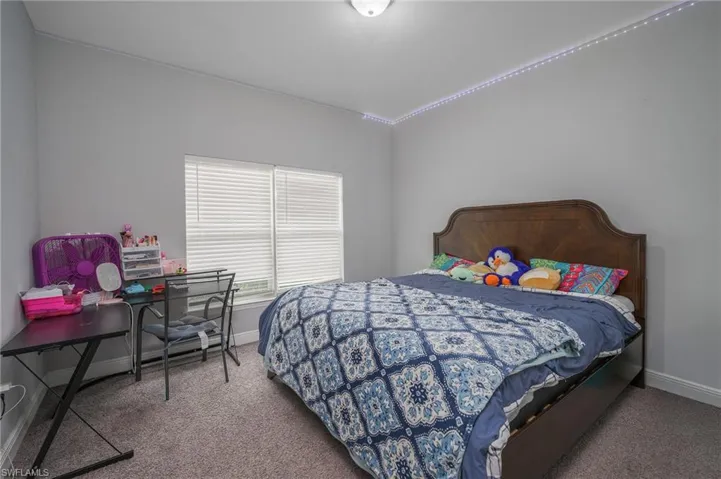 Bedroom featuring neutral gray walls, carpeting, and a dual-window configuration with blinds