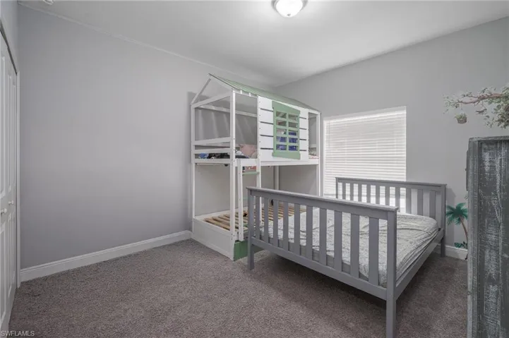 Light gray walls with white trim, gray carpet flooring, and a single window with horizontal blinds