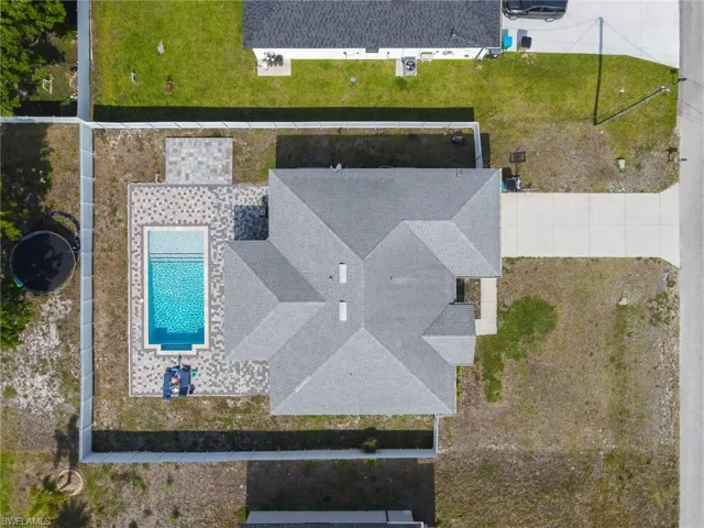 Aerial view showcasing a rectangular swimming pool surrounded by paver decking