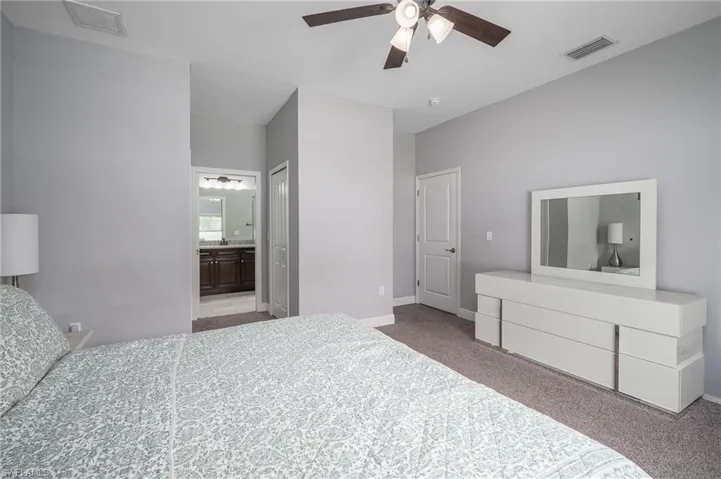 Carpeted bedroom with a vaulted ceiling and a ceiling fan