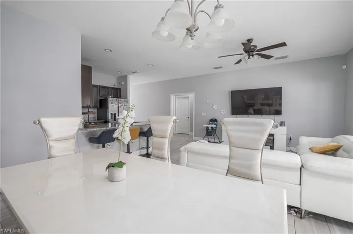 Open-concept living space featuring a modern chandelier, ceiling fan, and wood-finish flooring