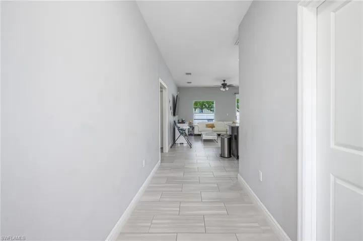 Hallway featuring wood-look tile flooring, light gray wall paint, and white baseboards