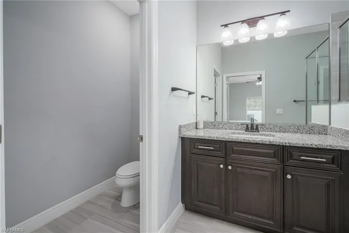 Bathroom featuring a dark wood-finish vanity with a granite countertop, undermount sink, and a large wall-mounted mirror