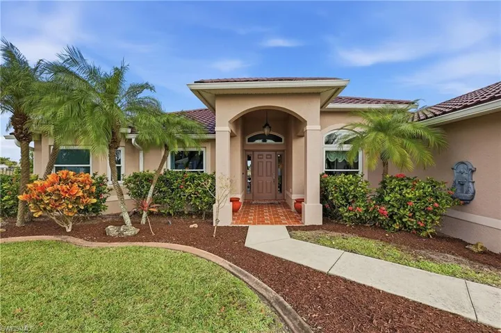 Doorway to property featuring stucco siding, a yard, and a tile roof