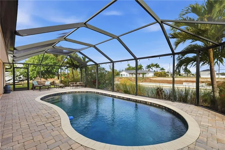 Outdoor pool with glass enclosure, a sunroom, a patio area, and an outdoor hangout area