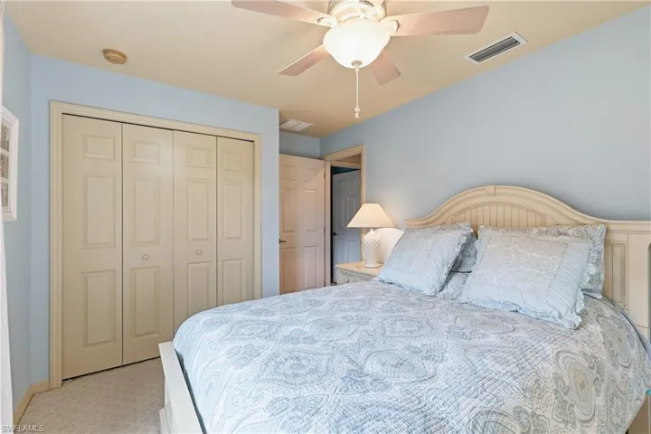 Bedroom with ceiling fan, a closet, and light carpet