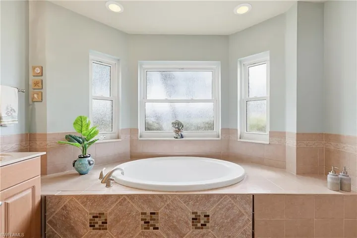 Full bathroom featuring a bath, vanity, healthy amount of natural light, and recessed lighting