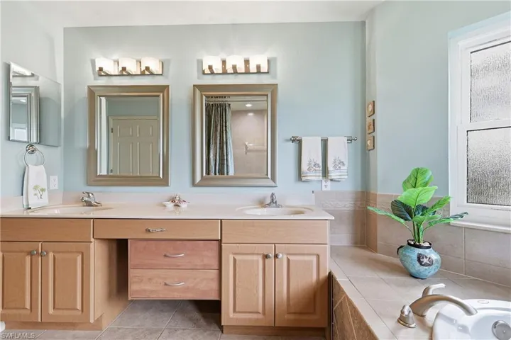 Bathroom with double vanity, a garden tub, light tile patterned floors, and a shower with curtain