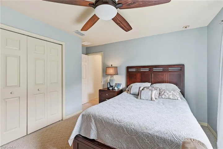 Bedroom with a closet, light carpet, and a ceiling fan