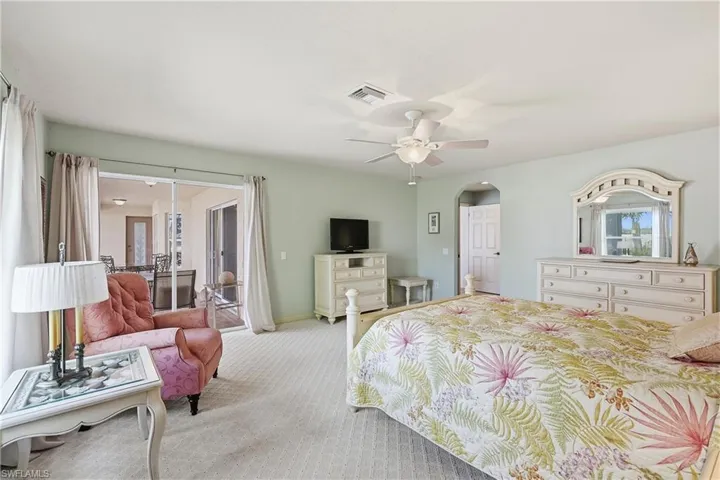 Carpeted bedroom with access to exterior, a ceiling fan, and arched walkways