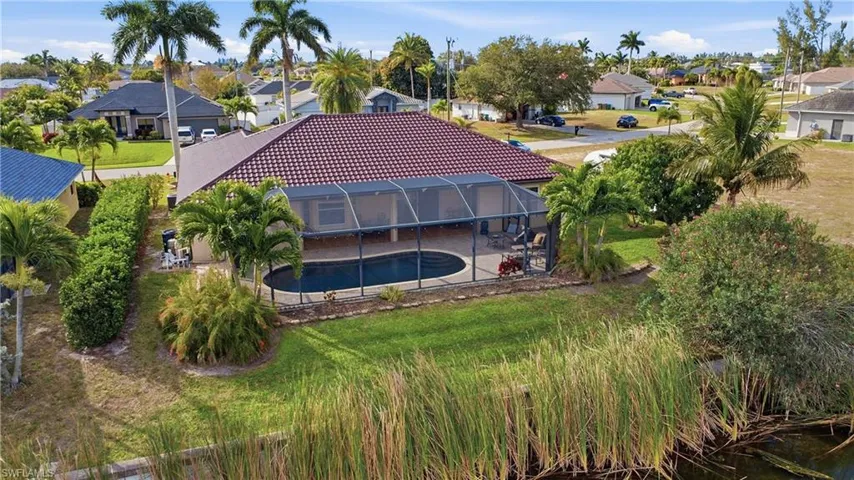 Back of property featuring an outdoor pool, a tile roof, a sunroom, a residential view, and a lanai