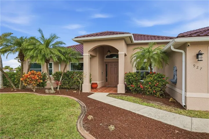 View of exterior entry featuring a lawn, stucco siding, and a tiled roof