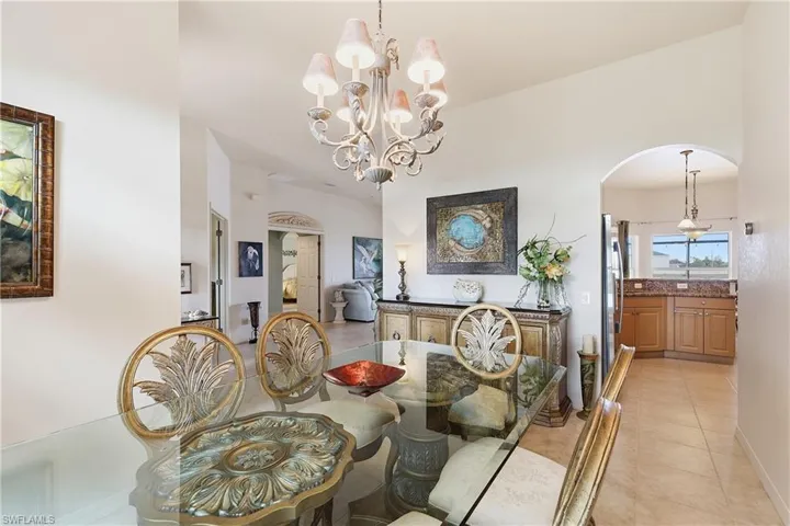 Dining room featuring arched walkways, light tile patterned floors, and a chandelier
