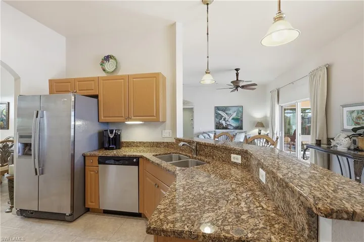 Kitchen with arched walkways, hanging light fixtures, a peninsula, a ceiling fan, and appliances with stainless steel finishes