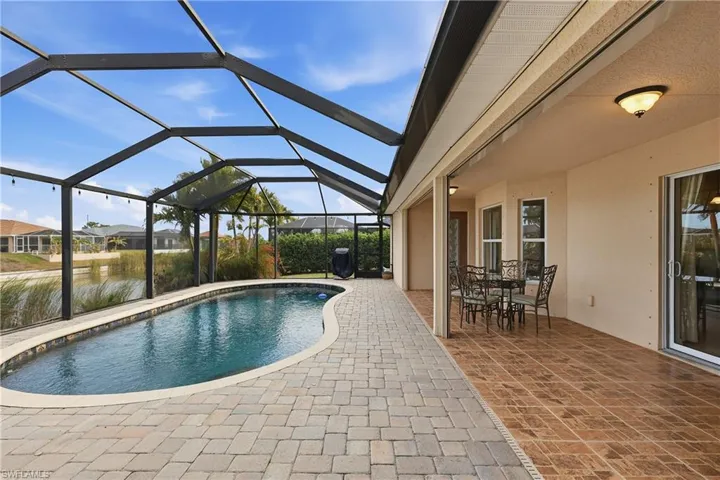 Outdoor pool with a sunroom, outdoor dining area, a patio area, glass enclosure, and area for grilling